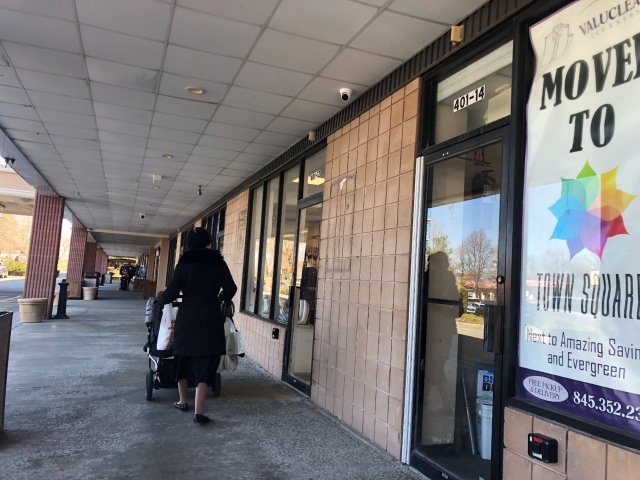 A woman pushes a stroller outside the Designer Spot, one of the establishments in Monsey where Rockland County officials say people were exposed to measles.