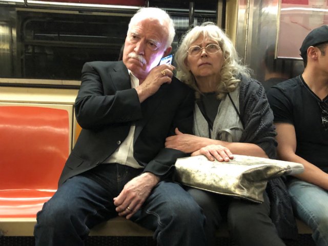 Two people listen to the Kavanaugh hearings on the subway today