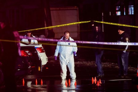 Police officers investigate the scene of the shooting in Queens