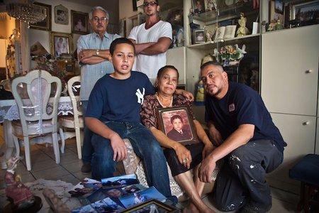 Carmen Perez is surrounded by family as she holds a portrait of her late son, Rolando Perez, who died at Rikers Island in 2014.