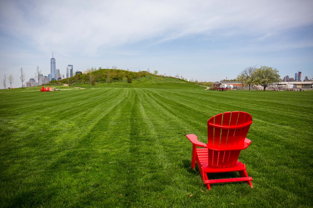9a1a557eegovisland-26-jpg.jpeg a red adirondack chair in a field