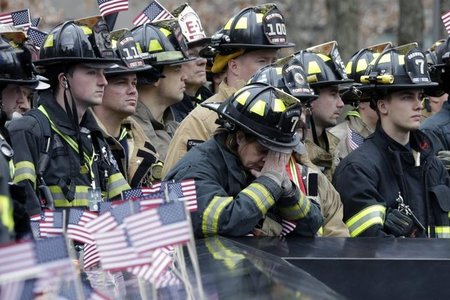 Firefighters observing a moment of silence in front of the 9/11 memorial in 2016