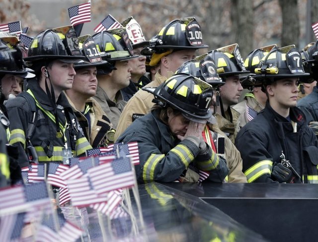 Firefighters observing a moment of silence in front of the 9/11 memorial in 2016