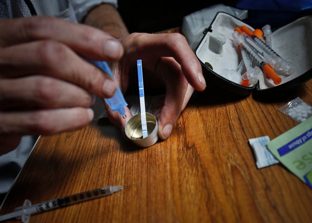 A heroin user places a fentanyl test strip in a mixing container to check for contamination.
