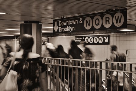 Commuters crowd in the 34th Street subway station near stairs to the platform level.
