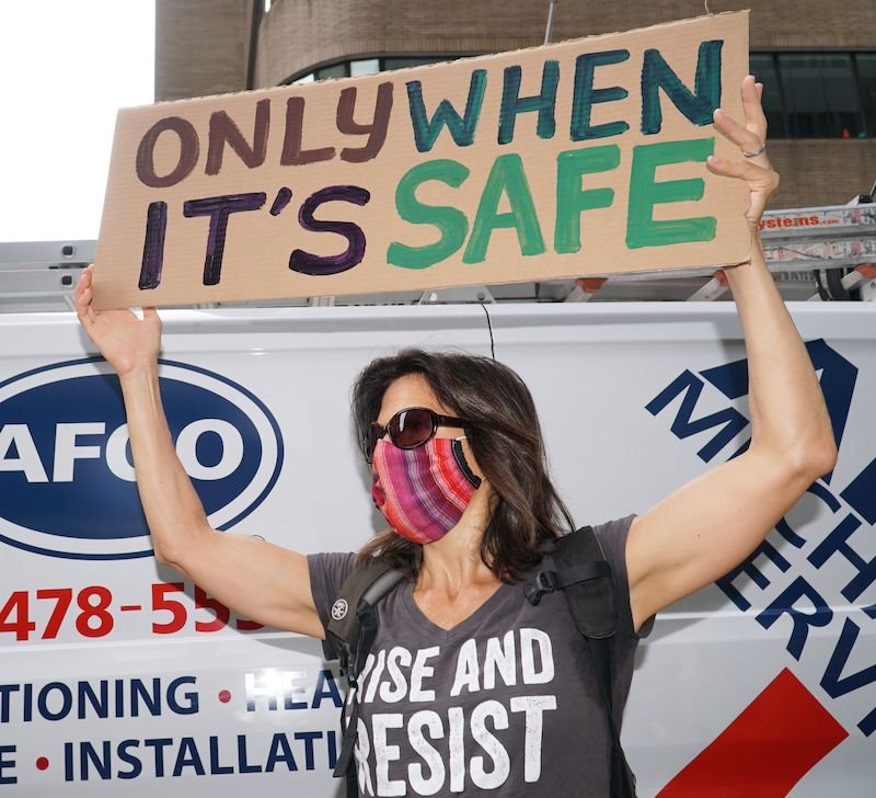 A woman holds a sign saying "Only When It's Safe" at the United Federation of Teachers office on August 3rd.